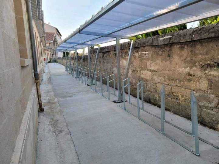 Abris vélo en charpente métallique mécano-soudée de 17 mètres de long, une toiture en bardage et des racks à vélos dans un lycée à bordeaux